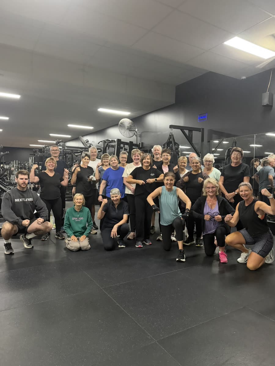 A large group of seniors flexing after their Tuesday morning exercise class